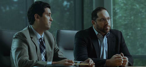 Two professionals in a meeting, seated at a table and engaged in discussion.
