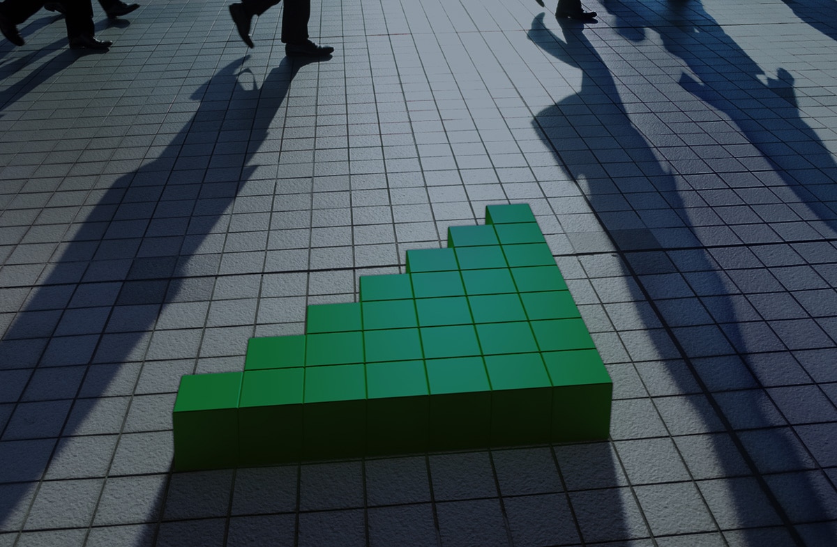 Green blocks forming an upward arrow on a tiled floor with shadows of people walking, representing growth or progress.