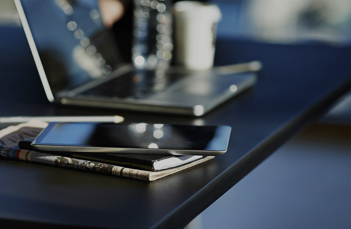 Close-up of smartphone on desk next to laptop.